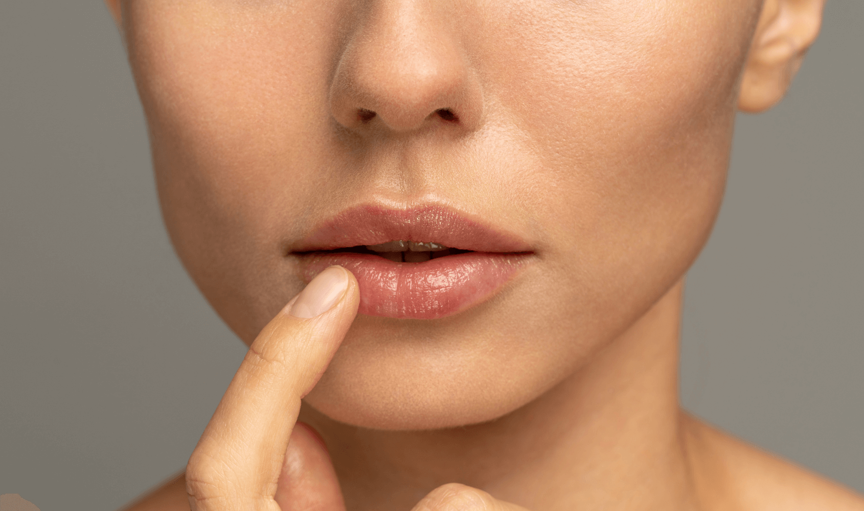 woman with lip fillers in Cardiff aesthetics clinic touching lips