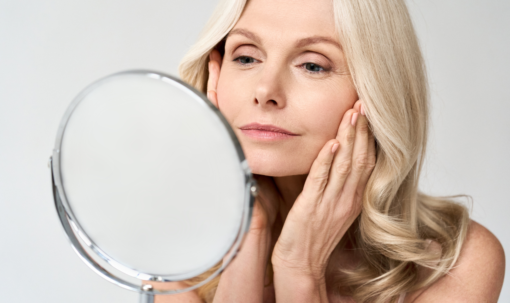 Woman looking in mirror after botox treatment.